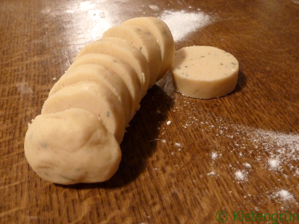 Teig für Rosmarin-Kekse zu einer Wurst gerollt und in Scheiben geschnitten