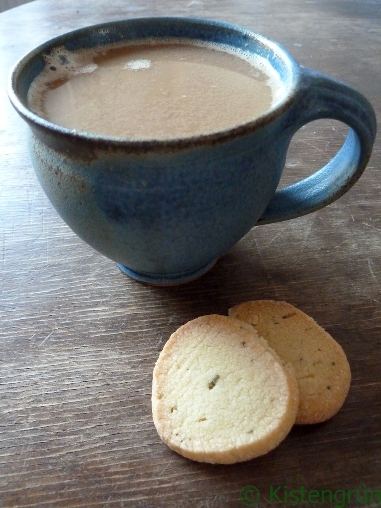 Eine blaue Tontasse mit Milchkaffee und zwei Rosmarin-Kekse