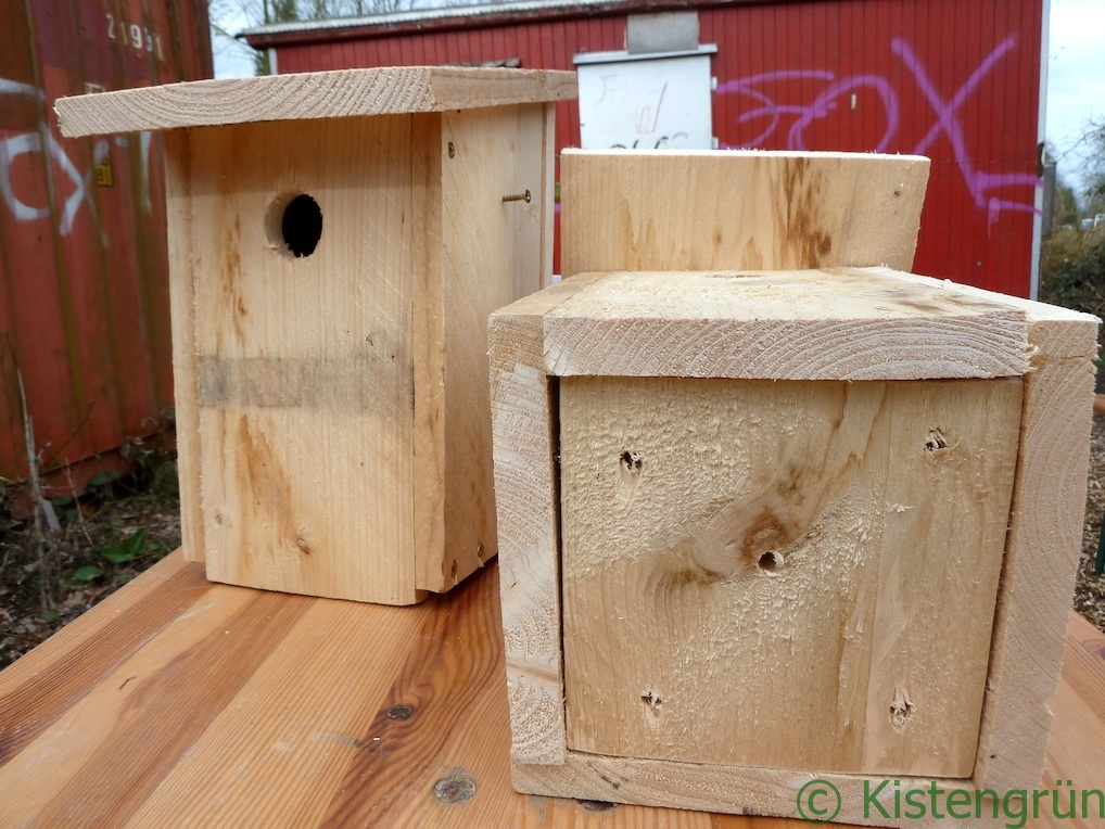 Zwei Meisenkästen stehen auf einem Holztisch.