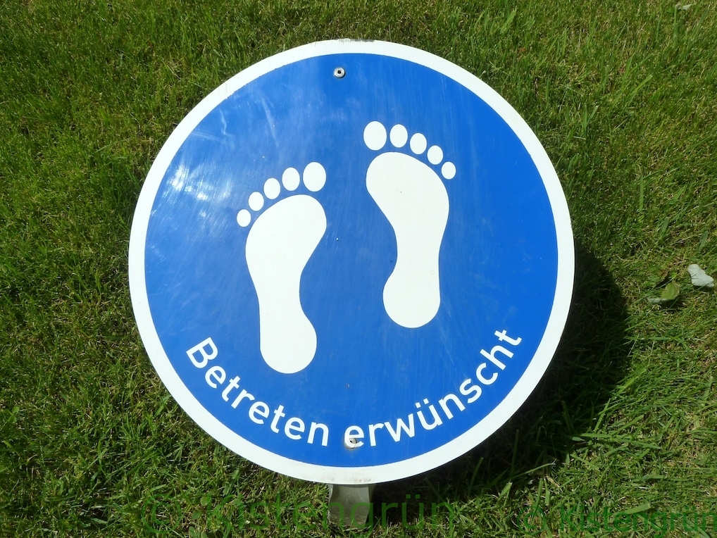 eine naues Schild mit der Aufschrift Betrten erwünscht und zwei füßen