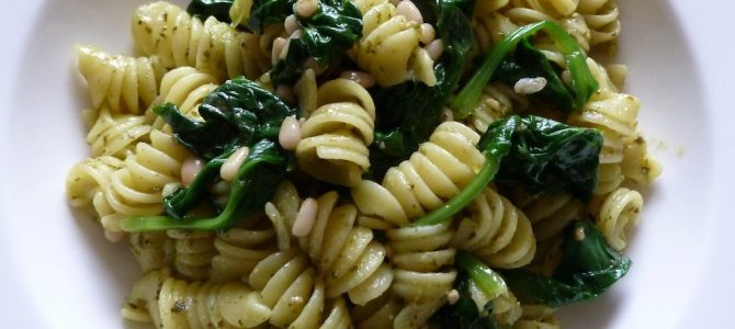 Pesto-Pasta mit blanciertem Spinat und Pinienkernen in einem weißen Teller