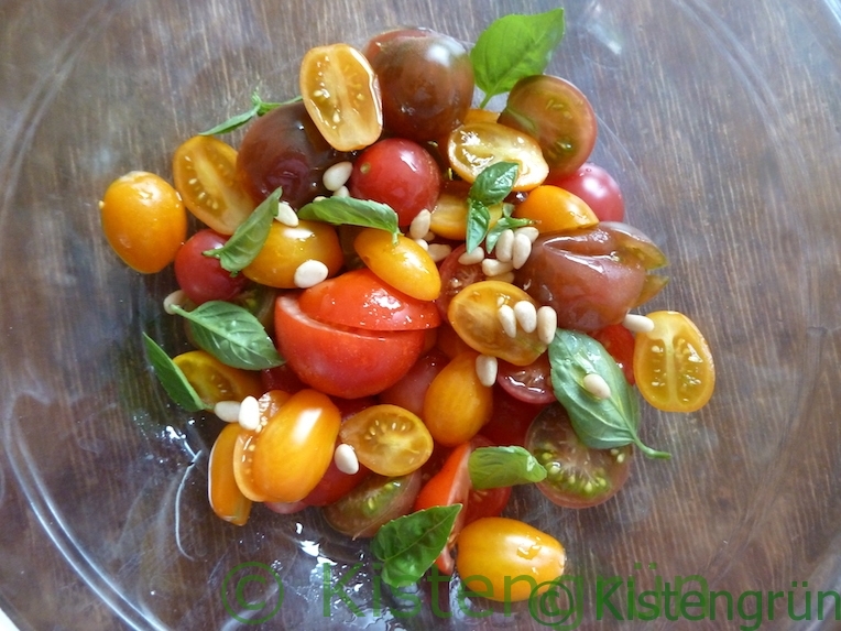 einfacher Tomatensalat mit Basilikum und Pinienkernen in einer Glasschüssel