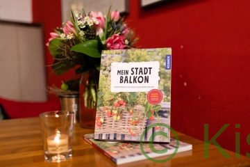 Das Buch Mein Stadtbalkon steht auf einem Tisch mit einem Blumenstrauß